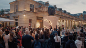 A live singer performing in front of the Giorgio Armani Sì immersive installation at dusk in London, with a large crowd watching and recording the event.